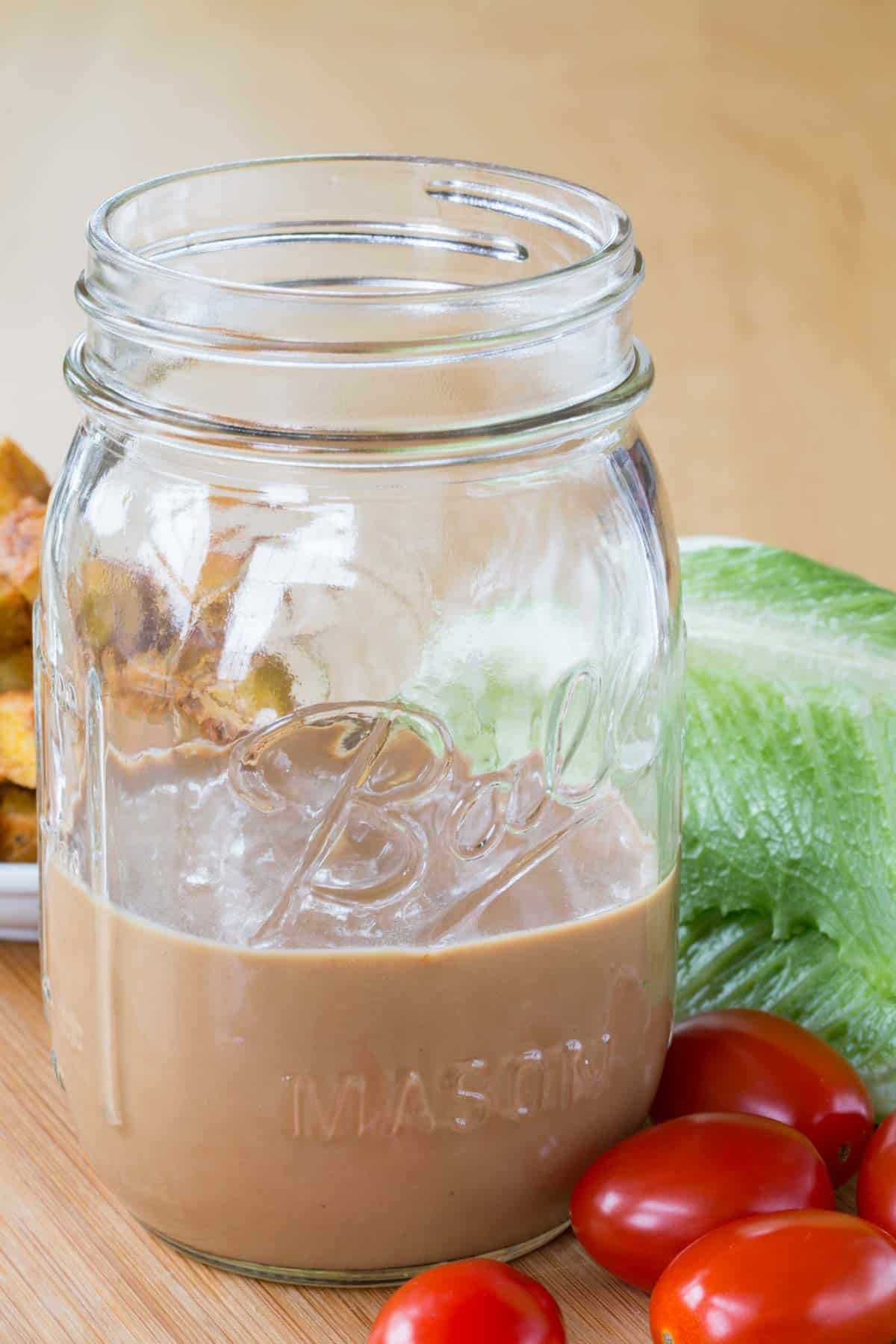 A glass ball jar about half full of a creamy salad dressing.
